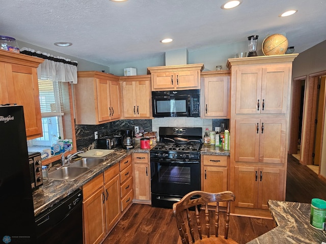 kitchen featuring dark stone counters, black appliances, decorative backsplash, sink, and dark hardwood / wood-style floors