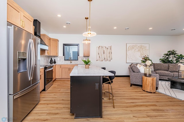 kitchen with tasteful backsplash, stainless steel appliances, light brown cabinets, a kitchen island, and light hardwood / wood-style flooring