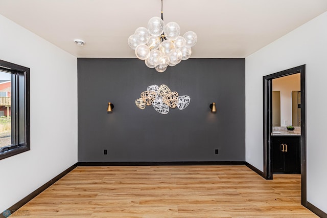 spare room featuring light hardwood / wood-style floors and a chandelier