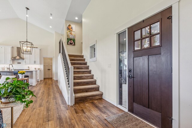 entryway featuring a notable chandelier, hardwood / wood-style floors, and high vaulted ceiling