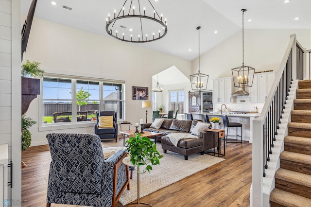 living room with an inviting chandelier, wood-type flooring, and high vaulted ceiling