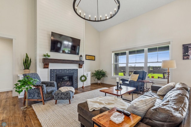 living room with a fireplace, wood-type flooring, a notable chandelier, and high vaulted ceiling