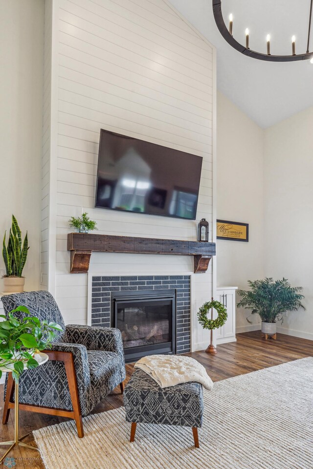 living room with high vaulted ceiling, a tiled fireplace, a chandelier, and wood-type flooring