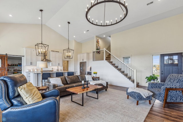 living room featuring an inviting chandelier, high vaulted ceiling, and light wood-type flooring