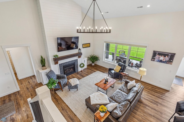 living room with brick wall, an inviting chandelier, wood-type flooring, and high vaulted ceiling