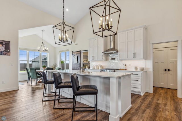 kitchen with dark hardwood / wood-style flooring, wall chimney exhaust hood, and an island with sink