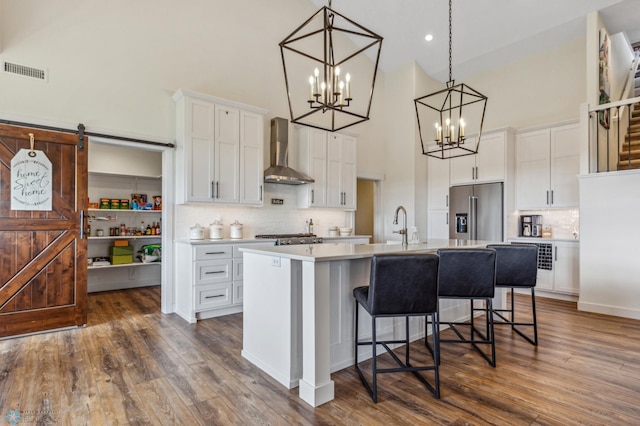 kitchen featuring white cabinetry, decorative backsplash, wall chimney exhaust hood, high end refrigerator, and dark wood-type flooring