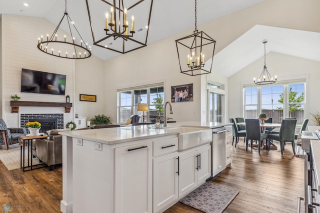 kitchen with a fireplace, dark hardwood / wood-style flooring, a notable chandelier, and an island with sink