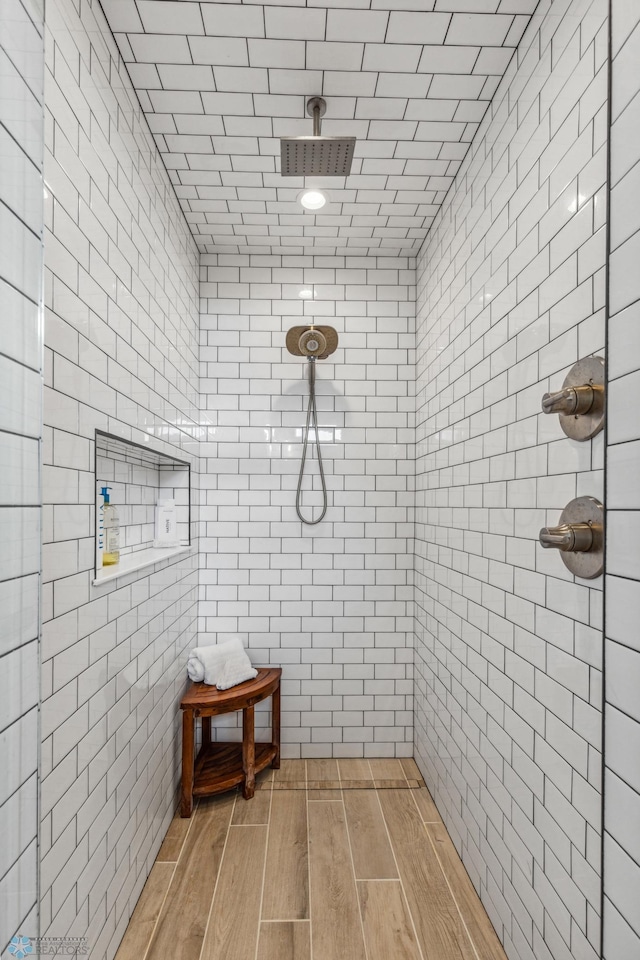 bathroom with tiled shower and hardwood / wood-style floors