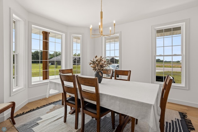 dining area featuring a healthy amount of sunlight, light hardwood / wood-style flooring, and an inviting chandelier