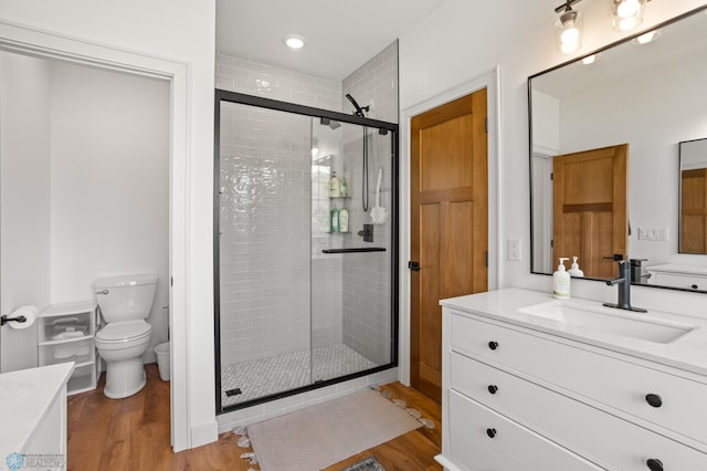 bathroom featuring vanity, walk in shower, toilet, and hardwood / wood-style floors