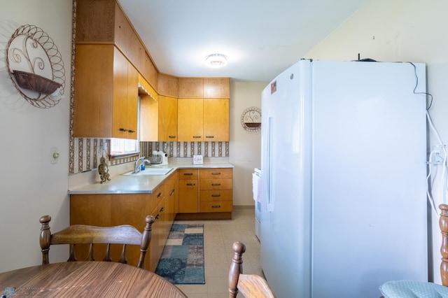 kitchen with white fridge, light tile patterned flooring, tasteful backsplash, light brown cabinets, and sink