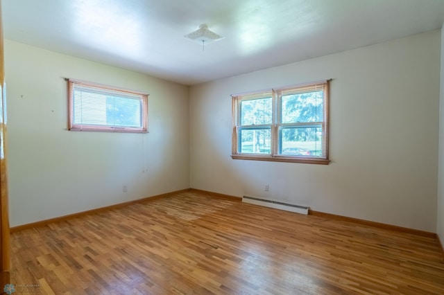 spare room featuring a baseboard heating unit and hardwood / wood-style flooring