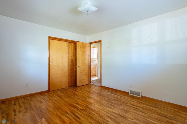 unfurnished bedroom featuring wood-type flooring and a closet