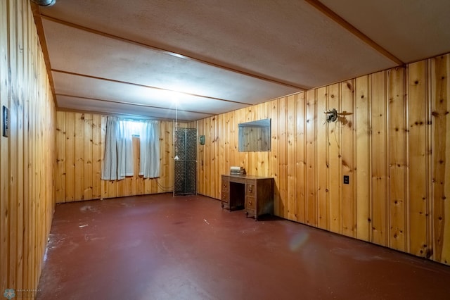 basement featuring a textured ceiling and wooden walls