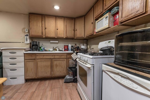 kitchen featuring sink, light wood-type flooring, and white appliances