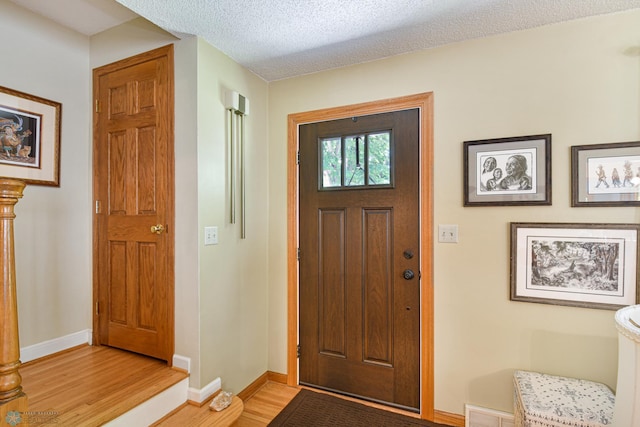 foyer with light wood-type flooring and a textured ceiling