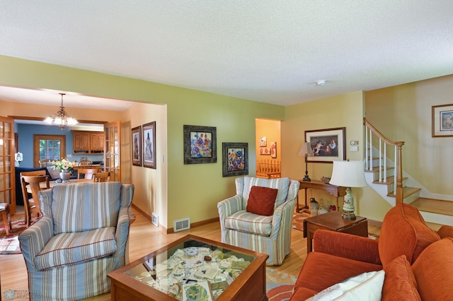 living room featuring a notable chandelier, light hardwood / wood-style floors, and a textured ceiling