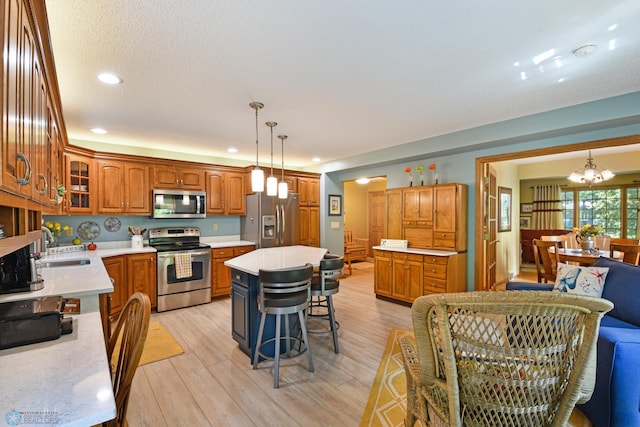 kitchen featuring pendant lighting, a breakfast bar area, a kitchen island, light hardwood / wood-style flooring, and stainless steel appliances