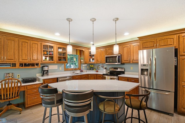 kitchen with built in desk, sink, a kitchen island, light hardwood / wood-style flooring, and stainless steel appliances