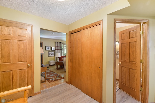 corridor with light hardwood / wood-style flooring and a textured ceiling