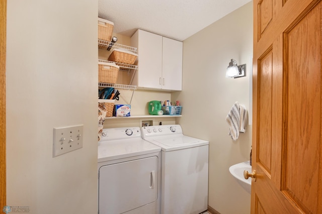 laundry area with a textured ceiling, washer and clothes dryer, and cabinets