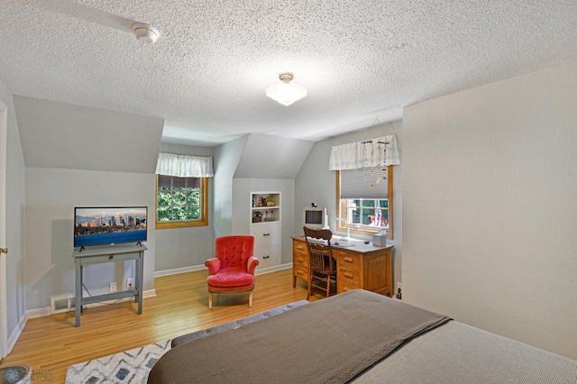 bedroom with light hardwood / wood-style floors, multiple windows, vaulted ceiling, and a textured ceiling