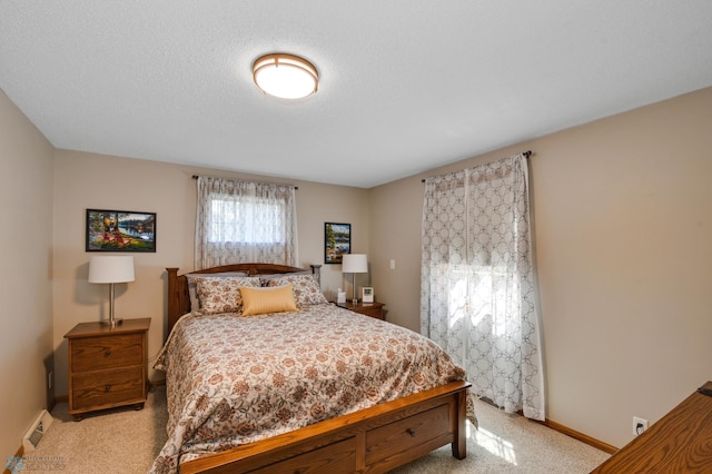 bedroom with light colored carpet and a textured ceiling