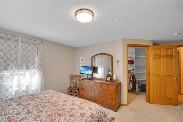 carpeted bedroom featuring a spacious closet, a closet, and a textured ceiling