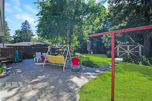 view of play area featuring a patio, a lawn, and a shed