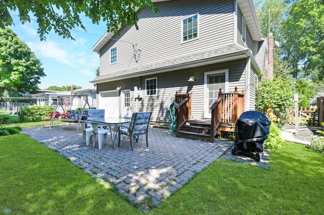 rear view of property featuring a garage, a patio, a deck, and a yard