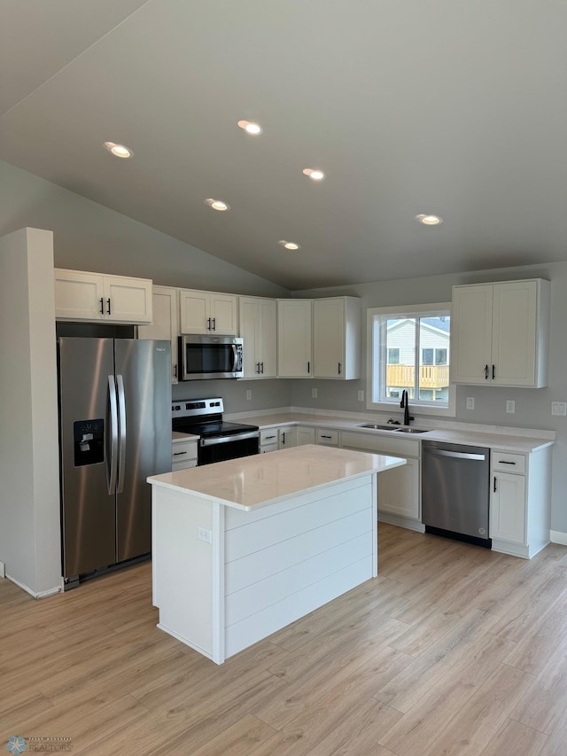 kitchen featuring white cabinetry, stainless steel appliances, a center island, light hardwood / wood-style flooring, and lofted ceiling