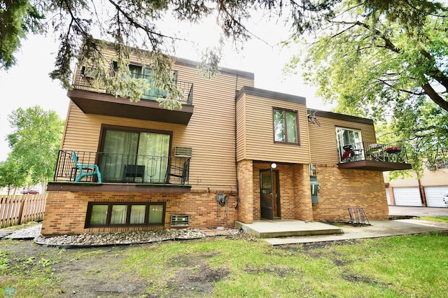 rear view of property with a patio, a balcony, and a garage