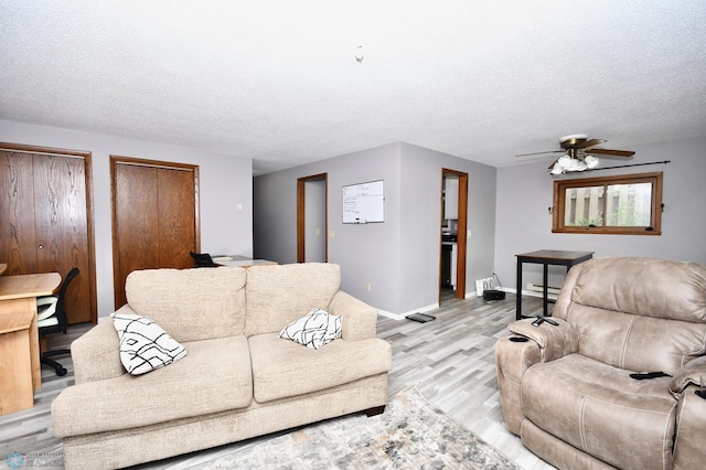 living room with ceiling fan, a textured ceiling, light hardwood / wood-style flooring, and a baseboard heating unit