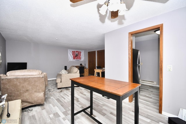 home office with a baseboard radiator, light hardwood / wood-style flooring, a textured ceiling, and ceiling fan