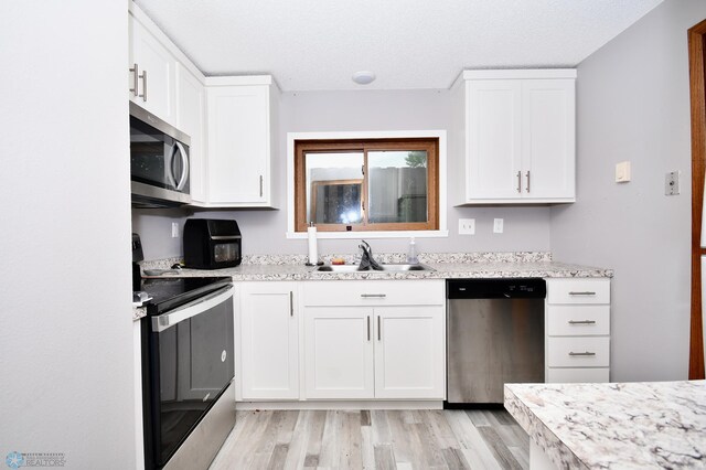 kitchen with light hardwood / wood-style floors, sink, white cabinets, and stainless steel appliances