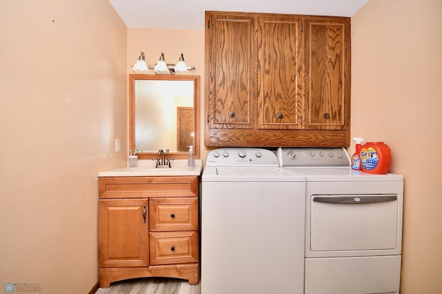 washroom with washing machine and clothes dryer, light wood-type flooring, sink, and cabinets