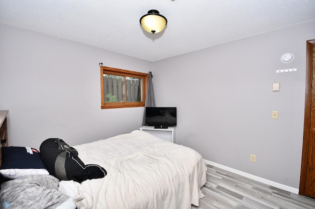 bedroom with a textured ceiling and light wood-type flooring