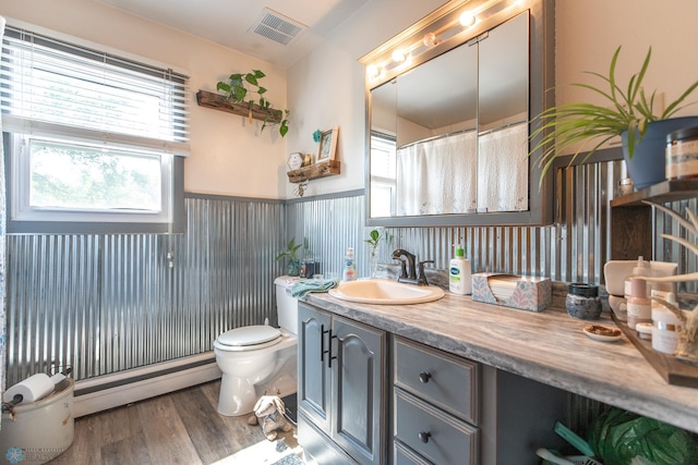 bathroom featuring vanity, hardwood / wood-style floors, baseboard heating, and toilet