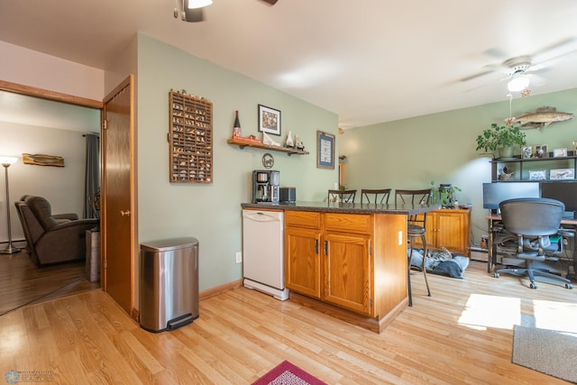 kitchen featuring a breakfast bar area, light wood-type flooring, kitchen peninsula, dishwasher, and ceiling fan