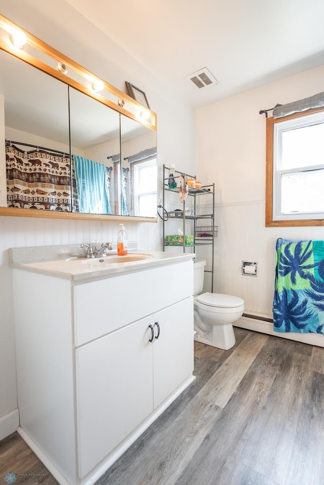 bathroom with hardwood / wood-style flooring, a wealth of natural light, toilet, and vanity