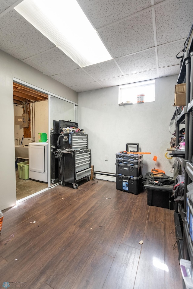 basement featuring washer / dryer, a paneled ceiling, hardwood / wood-style flooring, and a baseboard heating unit