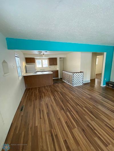 unfurnished living room featuring dark wood-type flooring and a textured ceiling