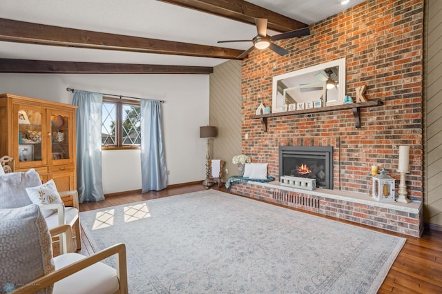 living room featuring ceiling fan, brick wall, a fireplace, wood-type flooring, and lofted ceiling with beams