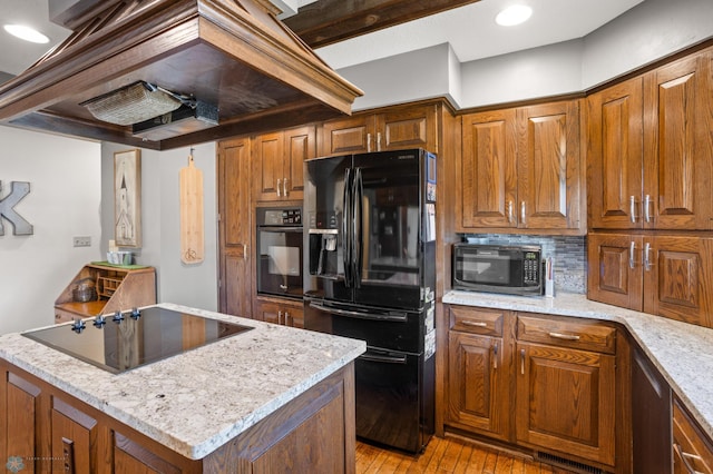 kitchen featuring light stone counters, light wood-type flooring, tasteful backsplash, and black appliances