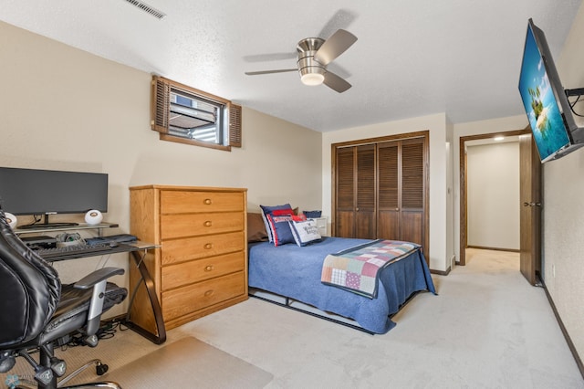 bedroom featuring light colored carpet, a closet, a textured ceiling, and ceiling fan