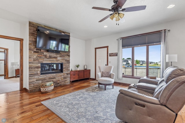 living room with ceiling fan, a fireplace, and light hardwood / wood-style floors