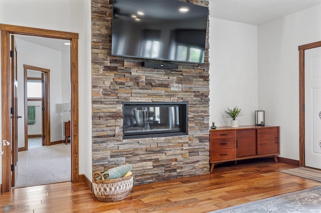 living room with light wood-type flooring, a wealth of natural light, and a stone fireplace