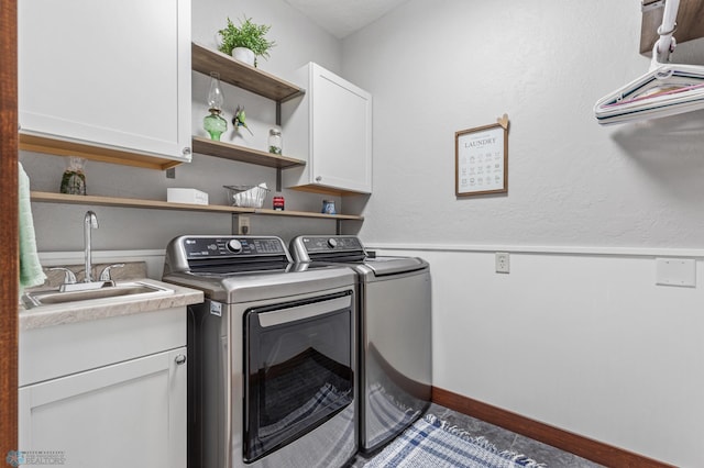 clothes washing area with cabinets, sink, and washing machine and clothes dryer