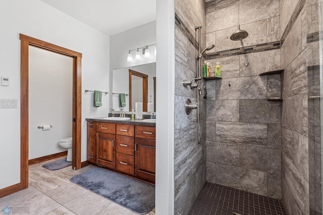 bathroom with tile patterned flooring, tiled shower, vanity, and toilet